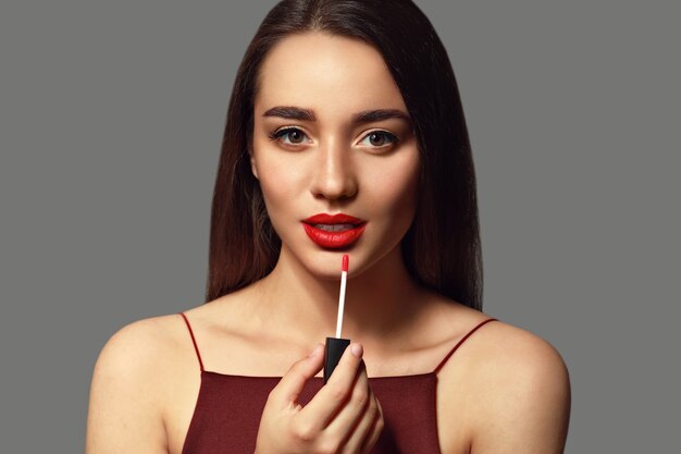 Beautiful young woman with bright lipstick on grey