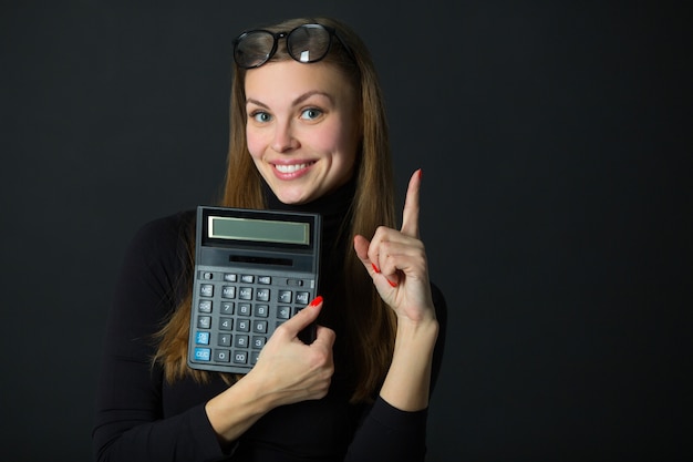 beautiful young woman with calculator on black background