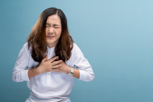 Photo beautiful young woman with chest pain standing against blue background