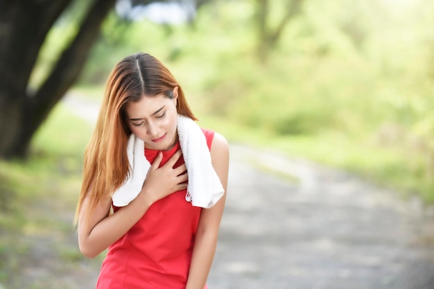 사진 가에 통증이 있는 아름다운 젊은 여성이 흐릿한 배경에 서 있습니다.