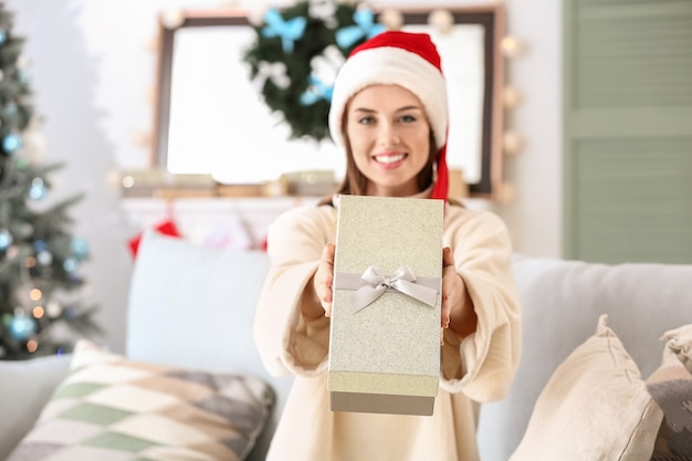 Beautiful young woman with Christmas gift at home