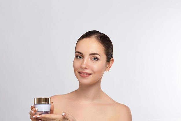 Beautiful young woman with clean fresh skin Girl holding cream in her hand Spa and face care