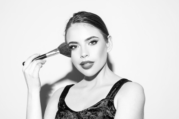 Photo beautiful young woman with clean fresh skin holding makeup brush applying tone to skin