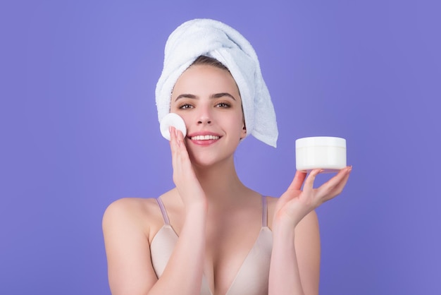 Beautiful young woman with cotton pad applying lotion on face removing makeup skin care studio portr