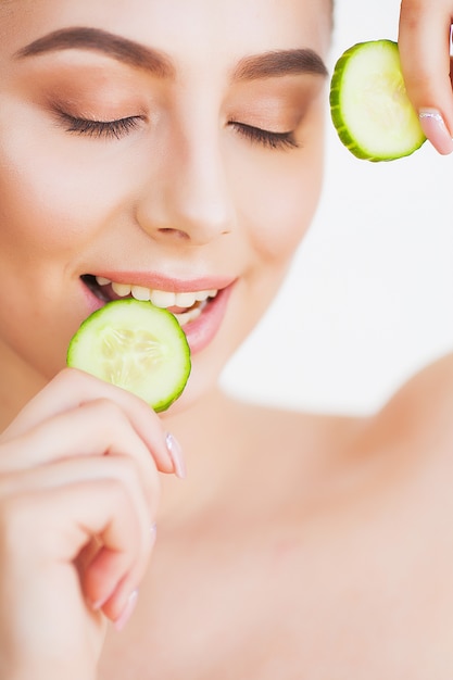 Beautiful young woman with cucumbers on eyes.