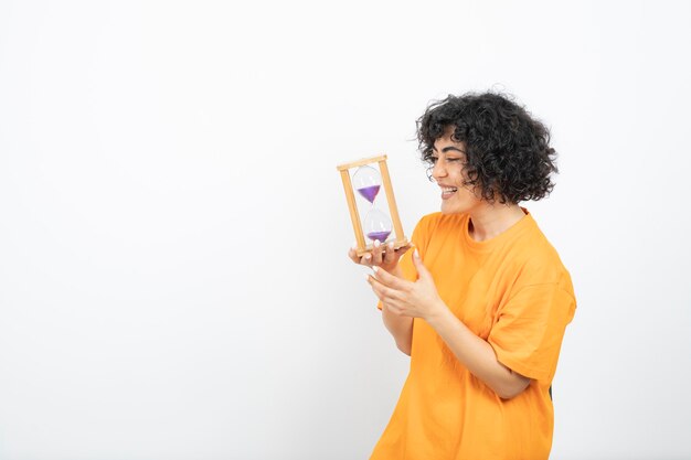 Beautiful young woman with curly hair holding hourglass .