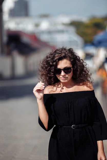 a beautiful young woman with curly hair walks through the city on a date in a black dress