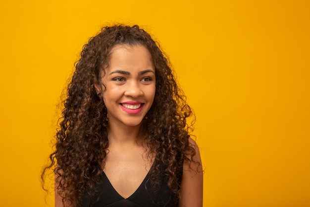 Beautiful young woman with curly hair on yellow 