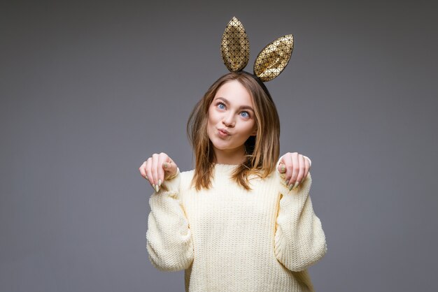 beautiful young woman with ears and funny facial expression posing on gray