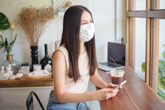 얼굴 마스크와 아름 다운 젊은 여자는 커피 숍에 앉아