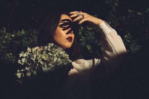 Beautiful young woman with fingers shadow on face in park at night