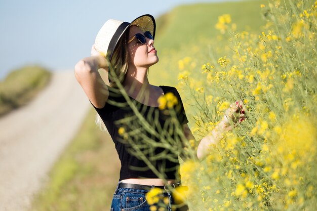 Bella giovane donna con fiori godendo estate in un campo.