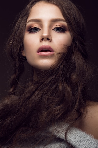 Beautiful young woman with gentle make-up in warm sweater and long straight hair