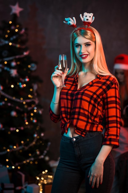 Beautiful young woman with glass of champagne at Christmas party