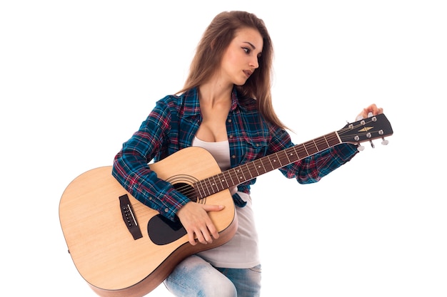 Beautiful young woman with guitar in hands isolated on white wall