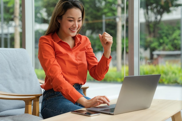 Beautiful young woman with happy screaming surprised face using laptop sitting on a coffee shop