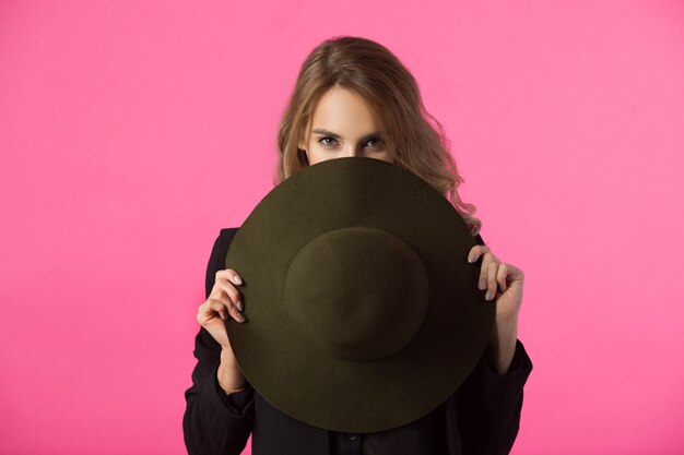 beautiful young woman with hat in hands with a serious facial expression