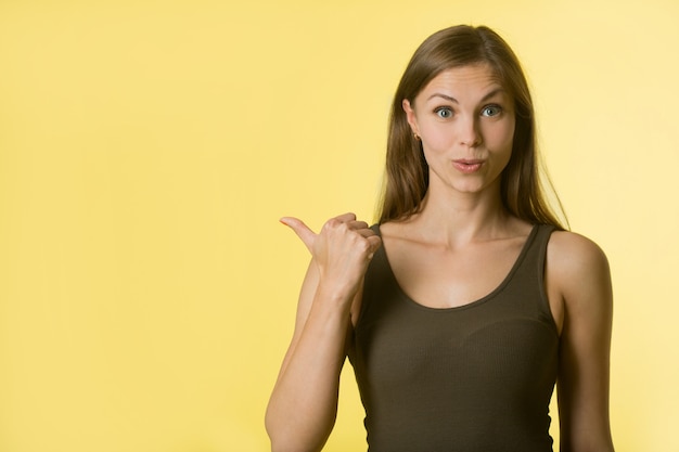 Foto bella giovane donna con i capelli sulla parete gialla con uno sguardo sorpreso