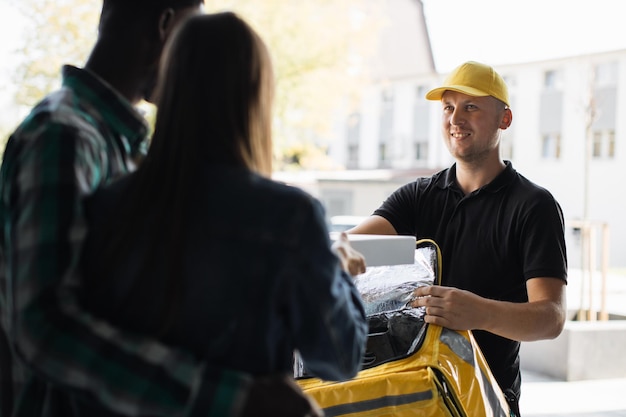 Beautiful young woman with her husband opening the door of their house and meets courier