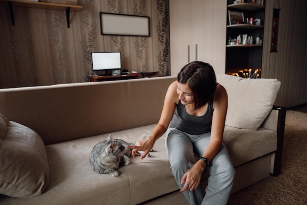 Bella giovane donna con un gatto di casa sul divano