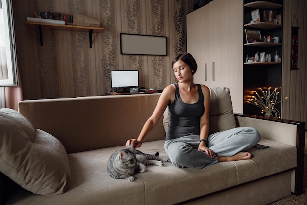 Beautiful young woman with a house cat on the couch