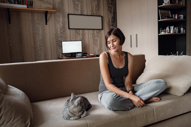 Foto bella giovane donna con un gatto di casa sul divano