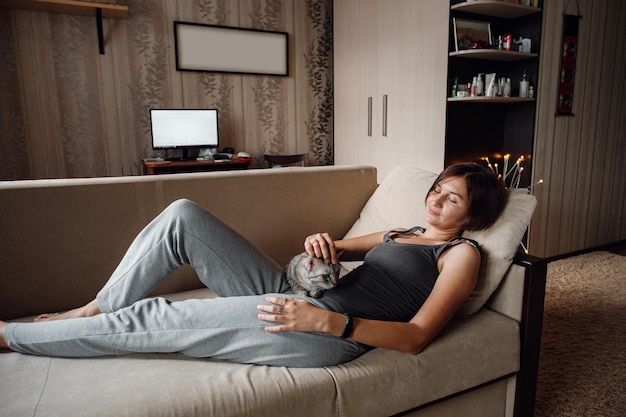 Beautiful young woman with a house cat on the couch