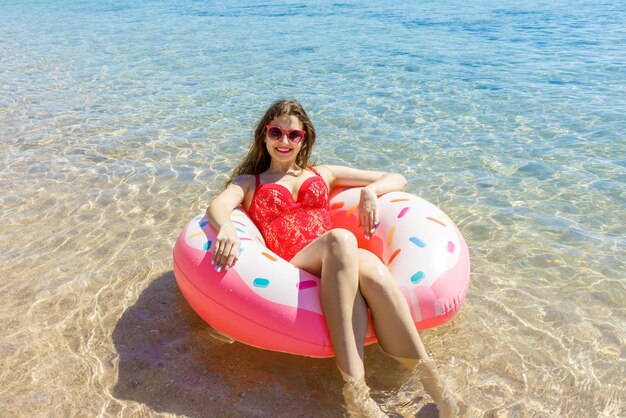 Beautiful young woman with inflatable donut in the sea