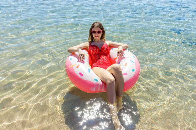 Beautiful young woman with inflatable ring relaxing in blue sea