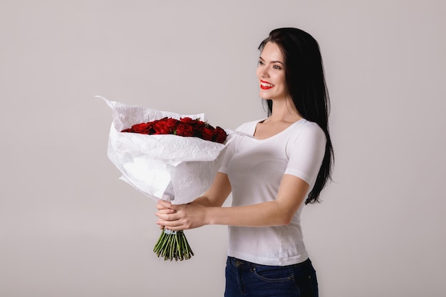 Beautiful young woman with a large bouquet of red roses