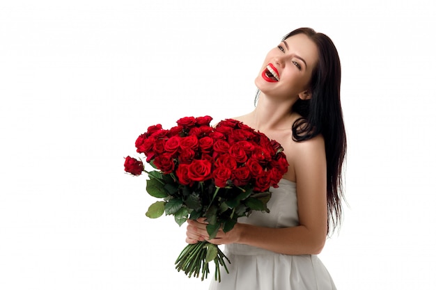 Beautiful young woman with a large bouquet of red roses
