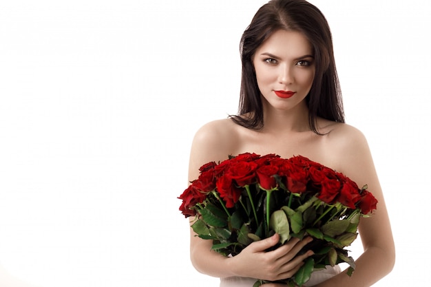 Beautiful young woman with a large bouquet of red roses