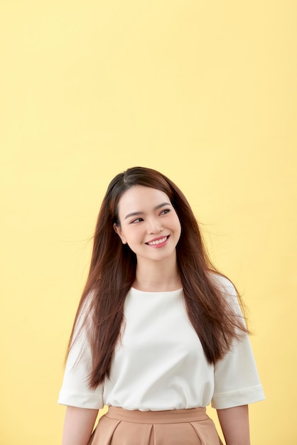 Beautiful young woman with long black hair posing on yellow background