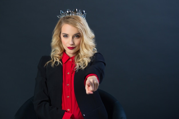 beautiful young woman with makeup in crown on black wall