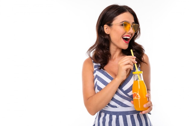 Beautiful young woman with perfect smile, sunglasses drinks juice and smiles, isolated on white background