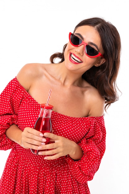 Beautiful young woman with perfect smile, sunglasses drinks strawberry juice and looks aside, isolated