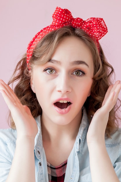 Beautiful young woman with pin-up make-up and hairstyle. Studio shot on pink.