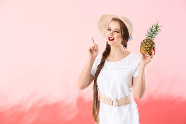 Beautiful young woman with pineapple on color