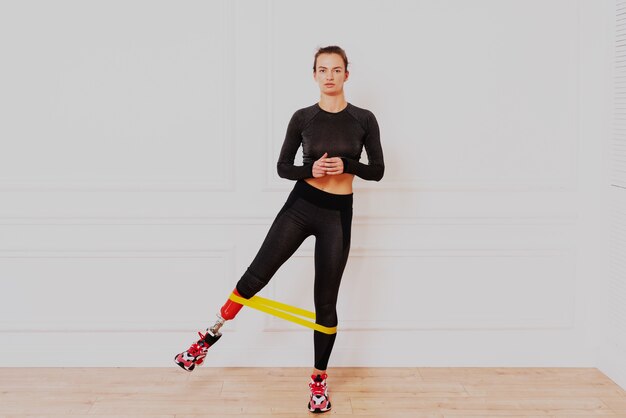 Beautiful young woman with prosthetic leg doing exercises