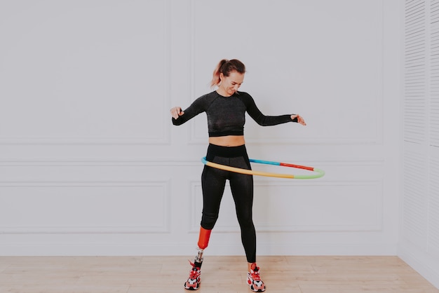 Beautiful young woman with prosthetic leg, using hula hoop