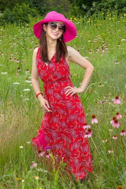 Foto bella giovane donna con fiori rossi sul campo