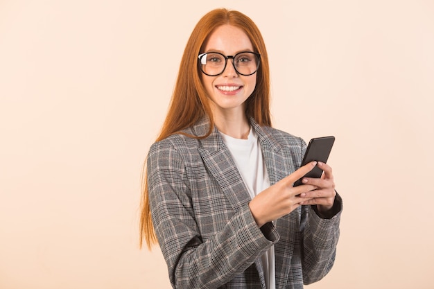 Beautiful young woman with red hair in a jacket on a beige background