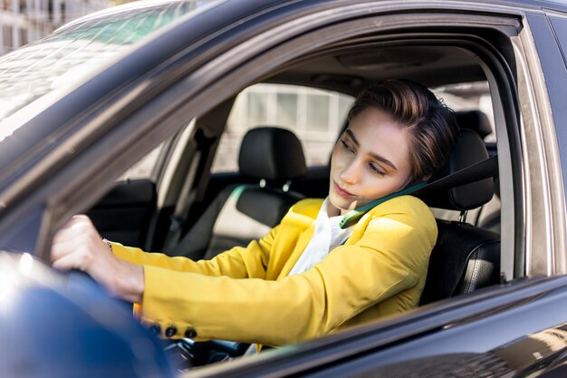 Beautiful young woman with short hair drives car in the city