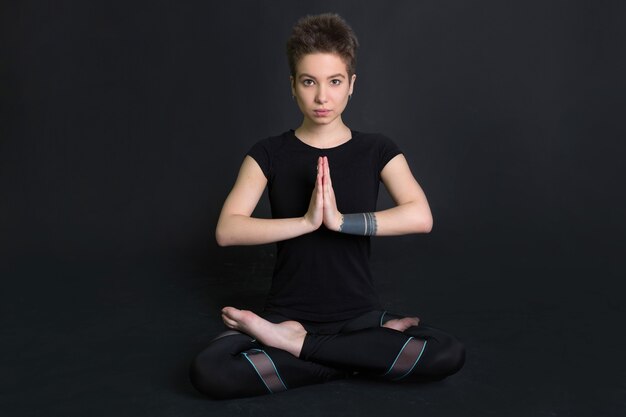 beautiful young woman  with a short haircut in a black t-shirt in a yoga pose