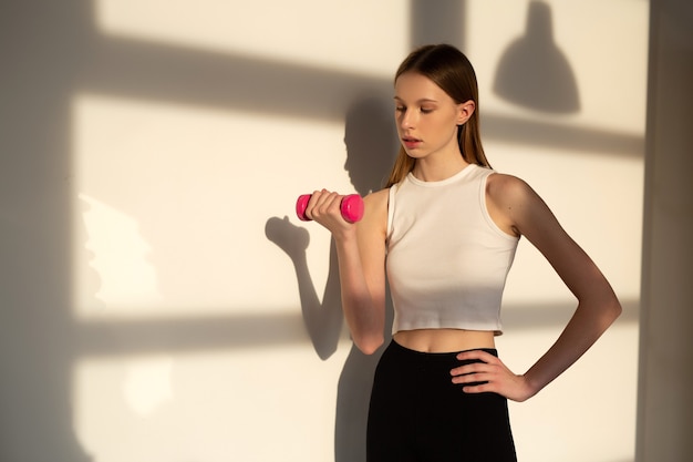beautiful young woman with a slim figure is engaged in a workout in the gym with dumbbells