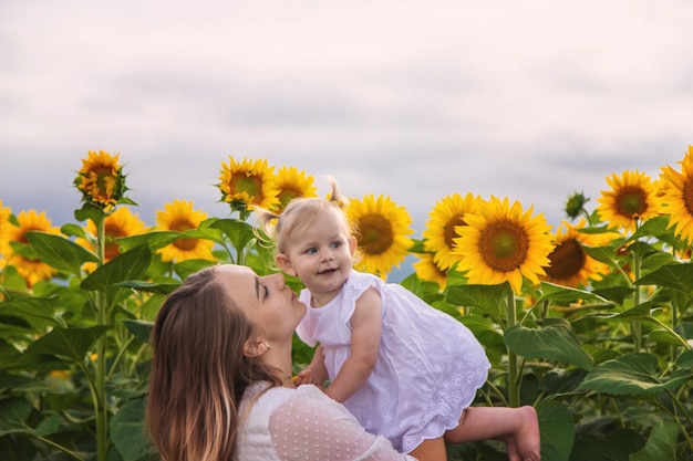 太陽<unk>の畑で小さな子供を抱いた美しい若い女性