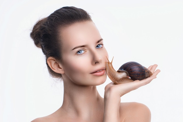 Beautiful young woman with snail on her face against white background skincare concept antiaging