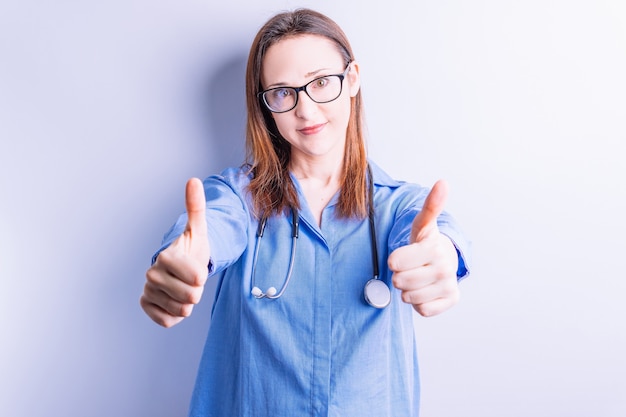 Photo beautiful young woman with stethoscope around her neck dressed casual raising thumbs up. medical student concept