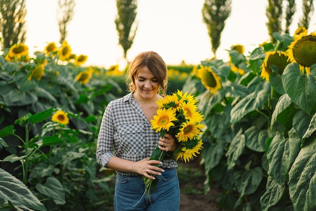 Beautiful young woman with sunflowers enjoying nature and laughing on summer sunflower field