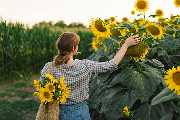 Beautiful young woman with sunflowers enjoying nature and laughing on summer sunflower field